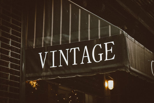 Enseigne de magasin vintage suspendue à un bâtiment. Un repère pour le sourcing vêtements vintage professionnel.