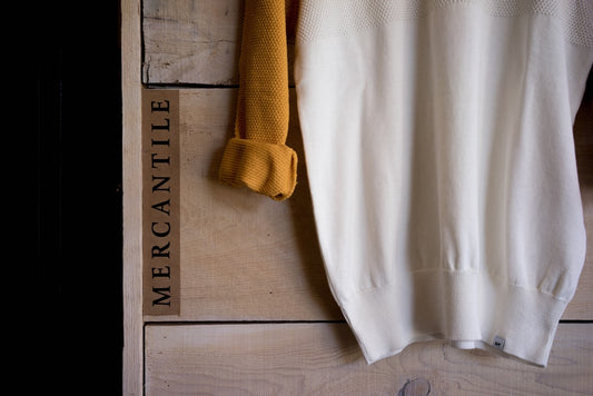 quel pull pour quelle morphologie - a white sweater hanging on a wooden wall